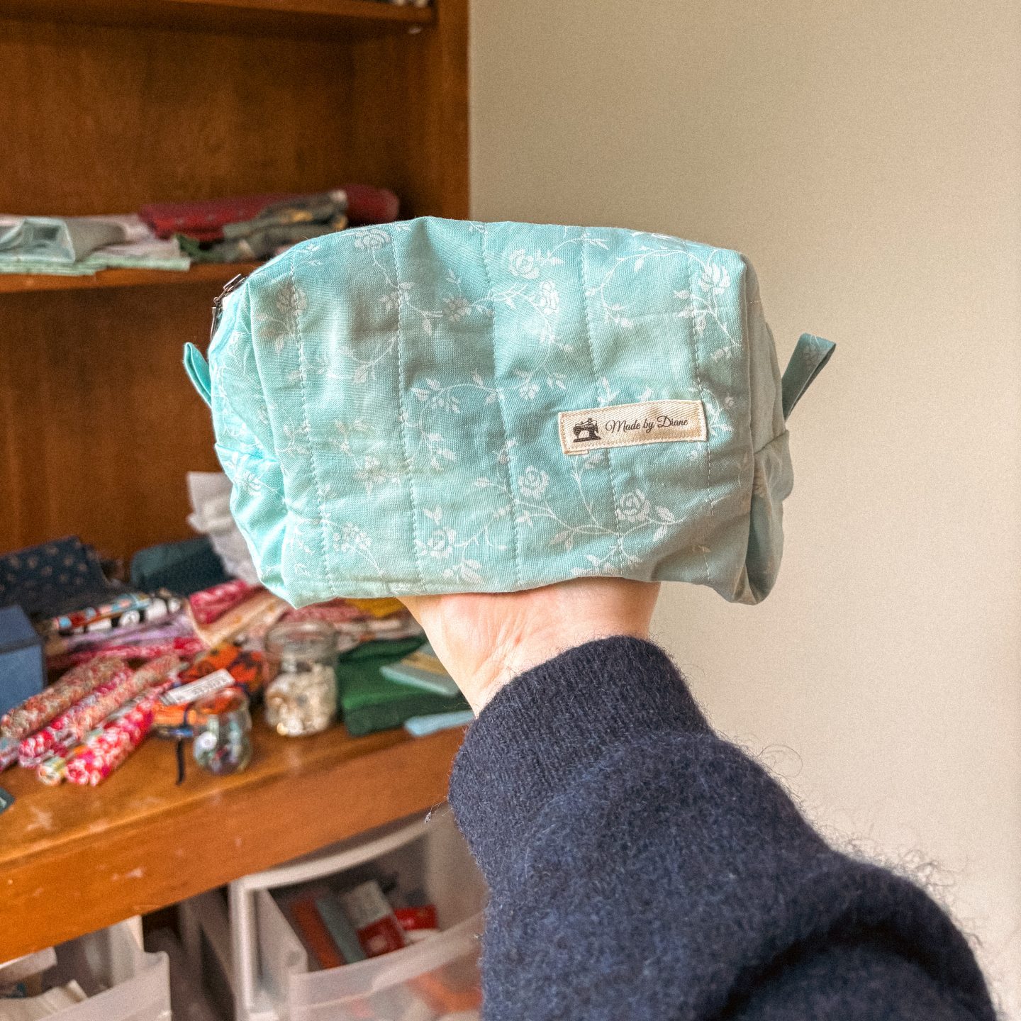 A quillted boxed zipper pouch with a Made by Diane label.